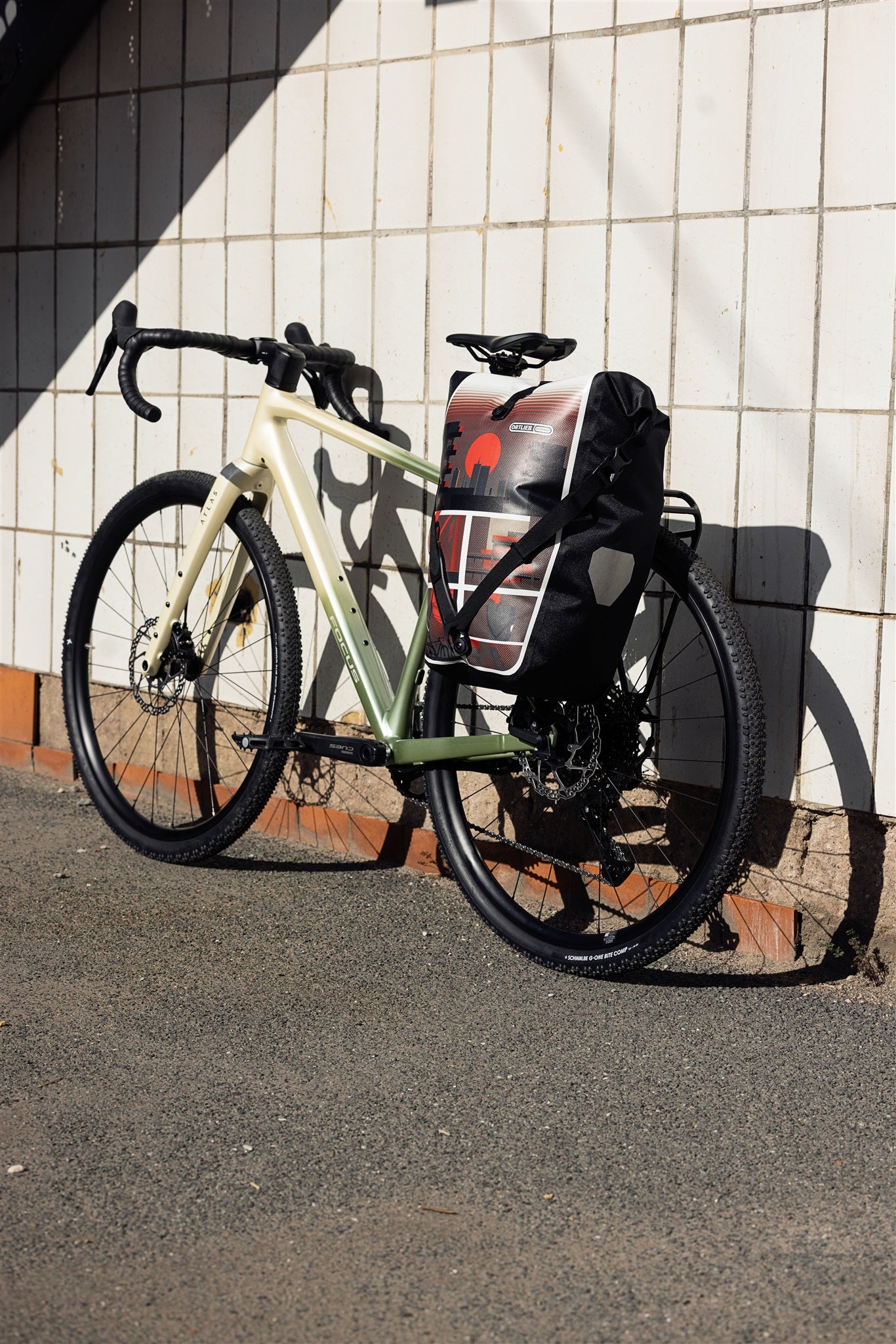 Vrouw met helm naast fiets met ORTLIEB Back-Roller Design tas in design "Morning Routine"